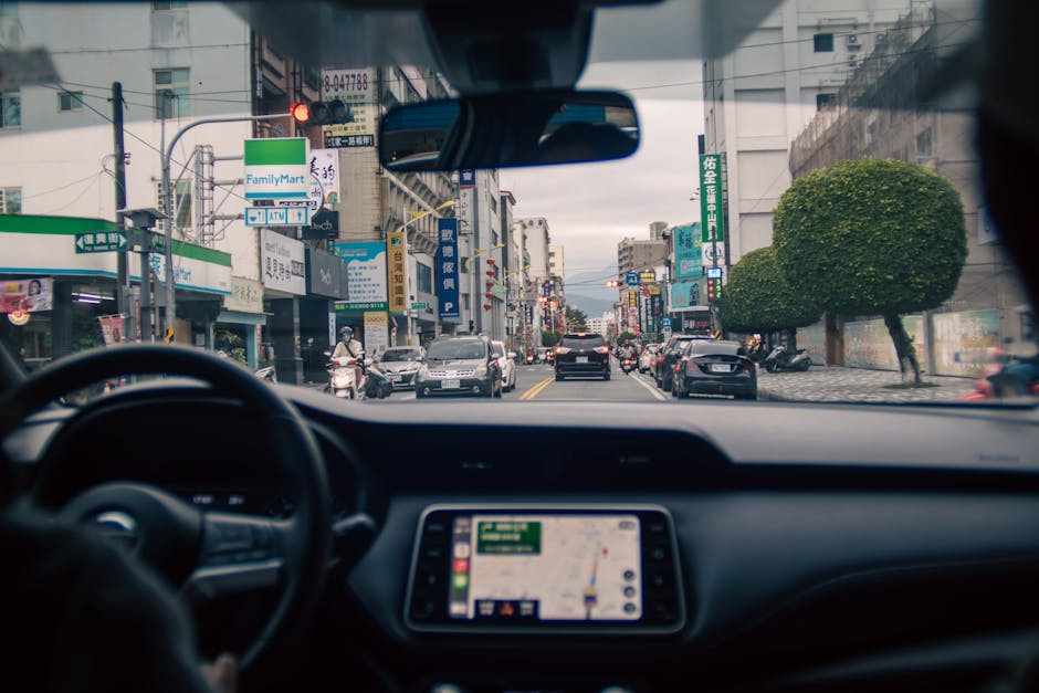 Urban street view captured from inside a car, showcasing city vibrancy and traffic.